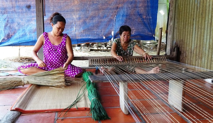 People weave mats using traditional wooden frames